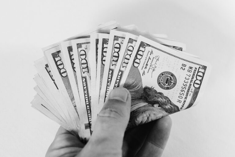 Auf dem Bild hält eine Hand Banknoten fest. Das Bild ist in schwarz-weiß.